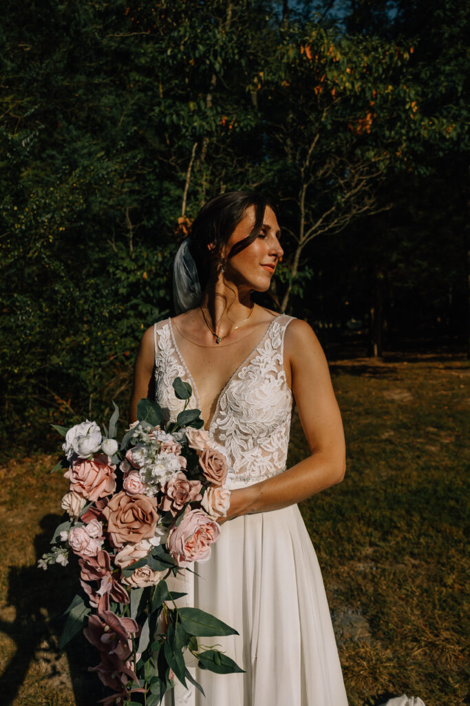 Bride glowing in sunlight, holding her pastel bouquet and looking serene